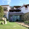 Una villa su due livelli con balconi, giardino curato e pietre decorative.