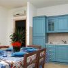 Cucina con mobili azzurri, tavolo apparecchiato e pianta al centro.
