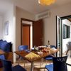 Sala da pranzo con tavolo apparecchiato, sedie blu e porte aperte su un patio esterno.