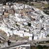 Una città storica con edifici bianchi arroccati su una collina.