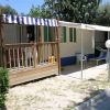 Una casa mobile con veranda in legno e tenda a righe blu e bianche, con sedie a sdraio.