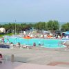 Piscina all'aperto con ombrelloni, sedie a sdraio e vista sul mare.
