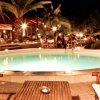 Piscina circolare illuminata di notte con palme intorno.