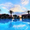 Piscina con palme al tramonto e cielo colorato.
