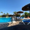 Piscina con lettini blu e ombrelloni di paglia.