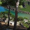 Spiaggia vista tra alberi e colline rocciose.