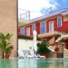Vista di una piscina con lettini e un edificio rosso a due piani con scale esterne e piante.