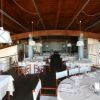 Un ristorante elegante con tavoli apparecchiati, sedie in legno e soffitto ad arco in legno.