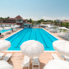 Una grande piscina all’aperto con ombrelloni bianchi e lettini intorno.