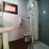 Bagno con doccia, lavandino e WC, pareti in legno bianco.