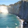 Una spiaggia con scogliera a picco sul mare e acque turchesi.