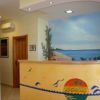 Reception con un bancone decorato e un murales di una spiaggia.