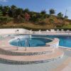 Piscina vuota con area idromassaggio, circondata da sedie a sdraio.