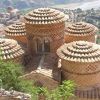 Un antico edificio con tetti circolari in mattoni e vista sul paesaggio.