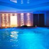 Piscina al coperto illuminata di blu, con pareti in pietra decorativa.