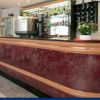 Bancone da bar elegante in legno scuro con bottiglie e tazze sullo sfondo.
