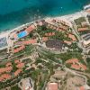 Vista aerea di un complesso turistico con edifici e una spiaggia.