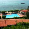 Piscina circondata da lettini, vicino a un edificio e al mare.