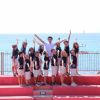 Gruppo di persone su gradini davanti al mare.