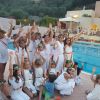 Bambini in abiti bianchi festeggiano accanto a una piscina.