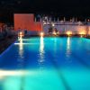 Piscina illuminata di sera con lettini e ombrelloni.