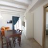 Sala con divano arancione, tavolo da pranzo, TV a parete e ingresso in una camera da letto.