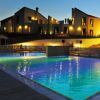 Piscina illuminata di sera, circondata da edifici residenziali e luci calde.