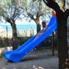 Bambini giocano su uno scivolo blu e una parete da arrampicata.