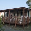 Una casa mobile in legno con veranda e sedie bianche.