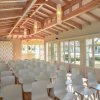 Sala con sedie bianche, soffitto in legno.
