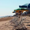 Spiaggia deserta con lettini e ombrelloni allineati.