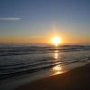 Tramonto sul mare con onde leggere e riflessi dorati in acqua.