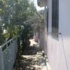 Un vialetto ombreggiato accanto a una casa con pareti rosa e finestre con persiane.