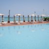 Piscina con ombrelloni e lettini, vista mare.
