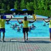 Tre istruttori guidano attività di fitness in piscina.