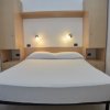 Letto matrimoniale con luci sopra, arredamento chiaro.