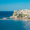 Città costiera su una scogliera con spiaggia e mare blu.