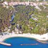 Vista aerea di una spiaggia sabbiosa con acque blu e un paese su una collina verde.