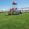 Un parco giochi con scivoli colorati su un prato verde, vicino a una spiaggia.