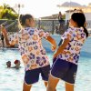 Due persone in magliette colorate danzano vicino a una piscina.