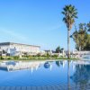 Una piscina serena con palme e sedie a sdraio sotto un cielo blu.