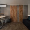 Soggiorno con tavolo bianco, sedie, divano nero, condizionatore a parete e decorazioni in legno.