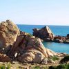 Massi di roccia scolpita affacciati su un mare blu.