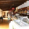 Un interno di bar con soffitto in legno, bancone con alcolici e una vetrina per gelato.