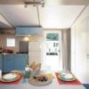 Cucina moderna con mobili azzurri, tavolo apparecchiato e frigorifero bianco.