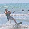 Un uomo pratica kitesurf sulle onde, tenendo saldamente la barra del kite.
