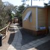 Casa mobile gialla con tende aperte, lungo un sentiero pavimentato nel verde.