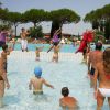 Persone in costume fanno attività in una piscina all'aperto con alberi intorno.