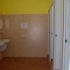 Bagno con lavandini bianchi, specchi tondi e pareti piastrellate beige.
