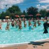 Persone che fanno acquagym in piscina con un'istruttrice in piedi.